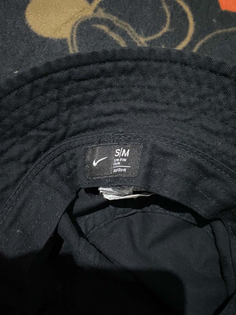 Nike Black Bucket Hat Size S/M (Category: Caps & Hats) located in Cebu City. Submitted by xyvielzyre (Listing ID 1466689762, Image 3). Description: Nike black bucket hat. Classic design with stitched brim and structured crown. Prominent Nike logo patch sewn on the front panel. Interior tag shows size S/M with Nike Swoosh branding. Lightweight cotton fabric, breathable construction. Ready to wear for casual outings or sunny days..