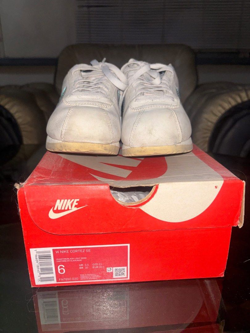 Nike Cortez SE Women's Phantom Black Light Bone (Category: Sneakers) located in Cavite. Submitted by ohitsaj (Listing ID 1466673330, Image 3). Description: Nike Cortez SE women's sneakers in phantom, black, and light bone colorway. Size US 6, UK 3.5, EUR 36.5. Features light blue swoosh detailing and black heel collar. Original Nike shoebox included. Soles show minor dirt from previous wear. Uppers show light creasing and dust..