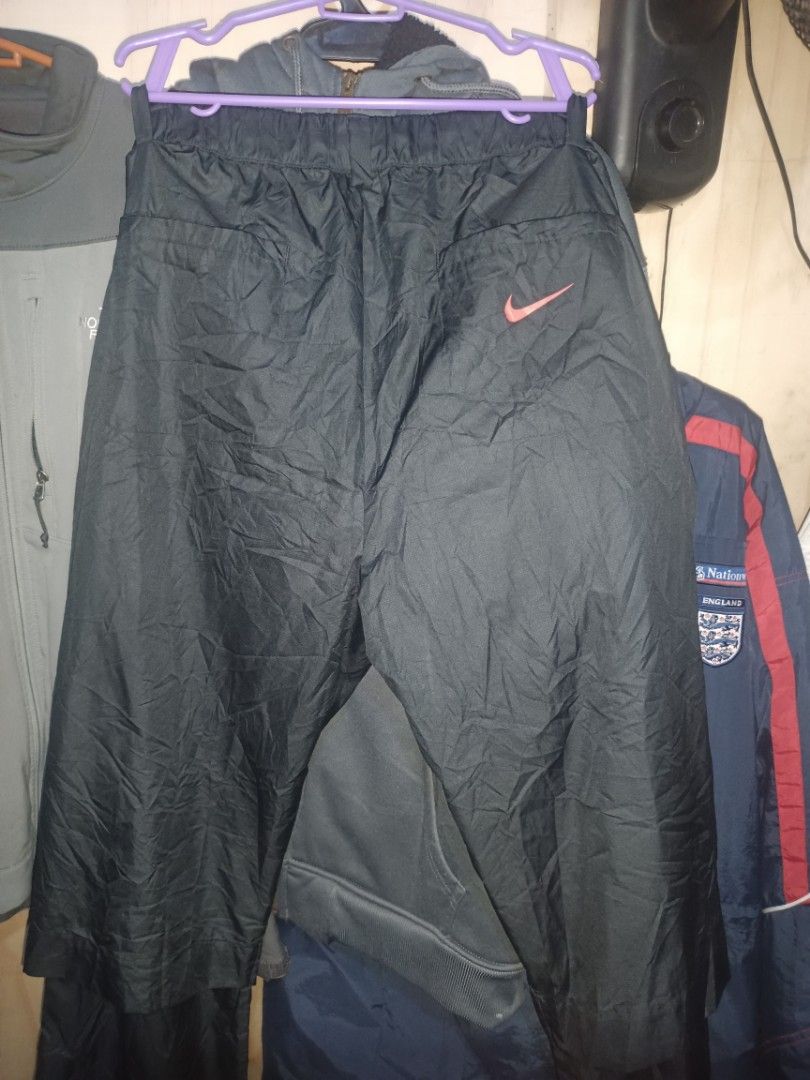 Nike Golf Black Track Pants (Category: Trousers) located in Manila. Submitted by rhoydyyy (Listing ID 1466651033, Image 3). Description: - Brand: Nike Golf - Color: Black with red accents - Size: Large (true to size) - Material: Lightweight, waterproof, packable - Features: Elastic waistband with drawstring, front red zipper pockets, subtle red Nike swoosh on back pocket - Origin: Made in Vietnam (nikebetterworld tag inside).