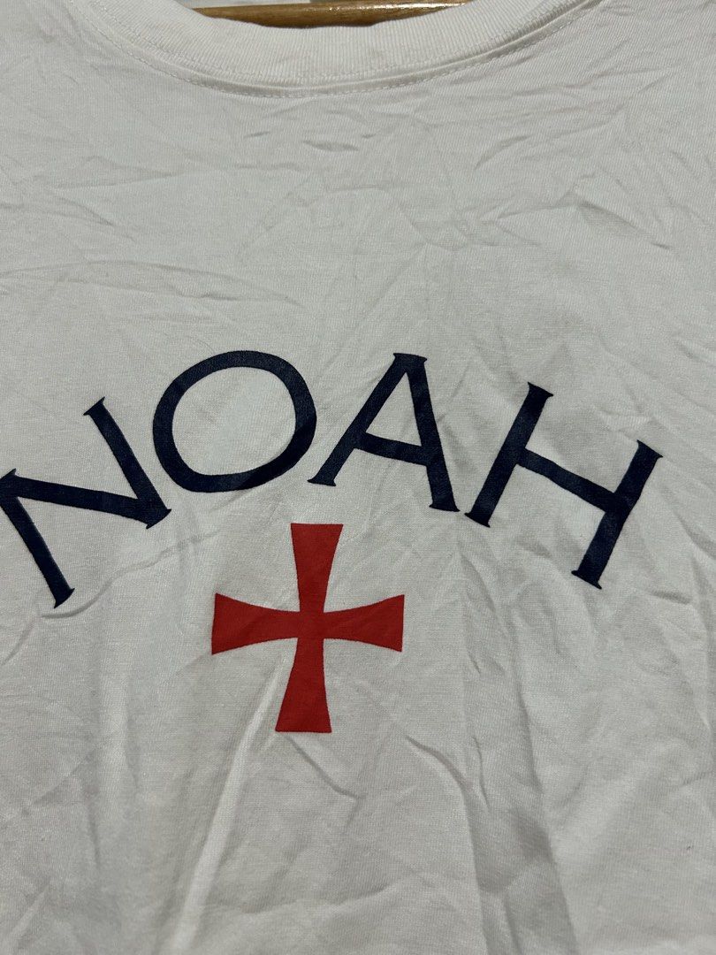 Noah White T-shirt with Cross Logo (Category: Tshirts & Polo Shirts ) located in Barotac Nuevo. Submitted by ehsherjohn27 (Listing ID 1466743336, Image 2). Description: - Brand: Noah - Color: White with navy blue lettering and red cross emblem - Material: 100% cotton (Made in Honduras) - Style: Classic crewneck, short sleeves - Condition: Good, with minor wrinkling from storage.
