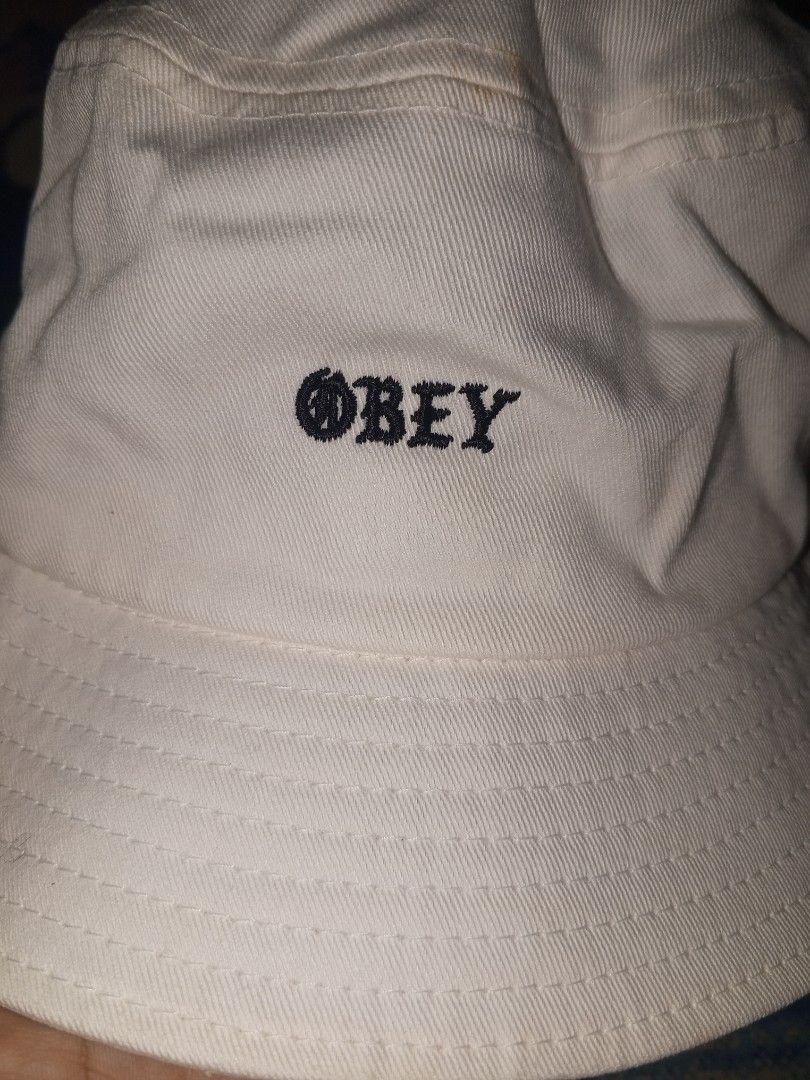 Obey Worldwide White Bucket Hat (Category: Caps & Hats) located in Magalang. Submitted by zeiansoria64090 (Listing ID 1466594679, Image 2). Description: - 100% breathable cotton material - Classic white color with black embroidered Obey Worldwide logo - One size fits all design - Clear brand and material tags inside - Ideal casual streetwear accessory for sunny days.