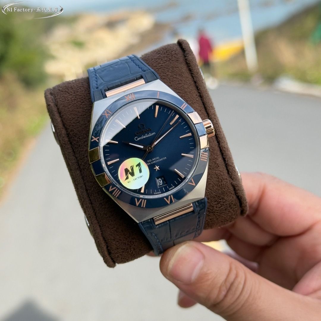 Omega Constellation Co-Axial Master Chronometer Blue Watch (Category: Men's Watches) located in Alabat. Submitted by aynunulema58877 (Listing ID 1466661436, Image 2). Description: Omega Constellation watch with a striking blue dial. Rose gold hands and hour markers pop against the deep blue background. Two-tone steel and rose gold case with matching roman numerals on the bezel. Blue leather strap with alligator texture. Date window positioned at 