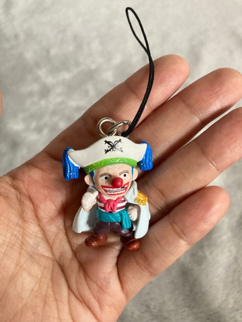 One Piece Buggy the Clown Figure Strap Keychain (Category: Character Goods) located in Rizal. Submitted by sheeraay (Listing ID 1466653620, Image 2). Description: - Character: Buggy the Clown from One Piece - Design: Marine captain outfit with white coat - Features: Includes black strap attachment and official copyright stamp on the back - Condition: Clean paint work and great overall condition - Type: Mini figure keychain.