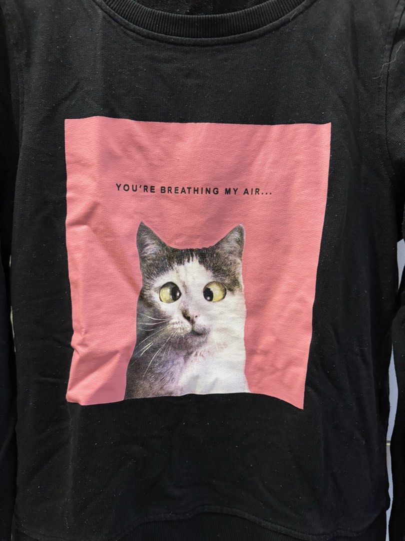 ONLY Black Cat Graphic Sweatshirt (Category: Longsleeves) located in Quezon City. Submitted by bubspreloved (Listing ID 1466703018, Image 2). Description: - Brand: ONLY - Size: XS - Color: Black - Design: Pink graphic square with funny cat face and 'YOU'RE BREATHING MY AIR...' text - Style: Crew neck, long sleeves, ribbed cuffs and hem - Material: Comfortable cotton blend - Condition: Excellent / As good as new - Perfect for everyday casual wear.