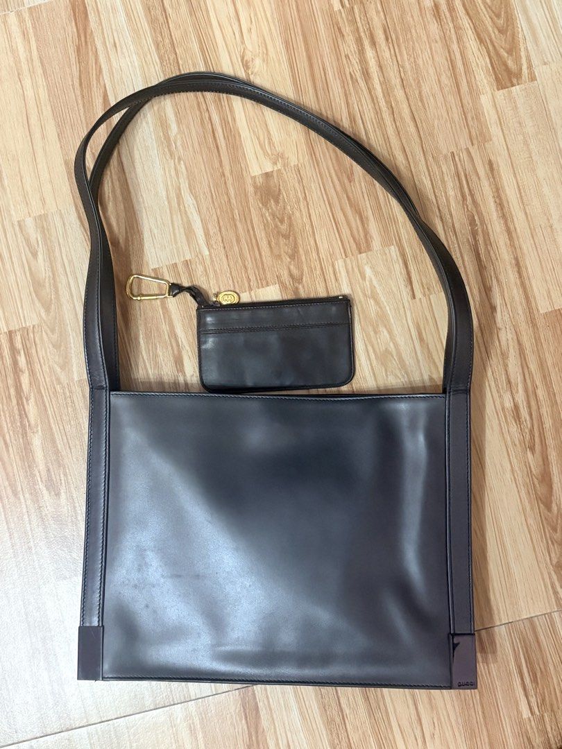 ORIGINAL Gucci dark leather shoulder bag with small pouch (Category: Luxury Bags & Wallets) located in Bacoor. Submitted by preownedparadyse (Listing ID 1466753612, Image 1). Description: - Authentic Gucci dark leather shoulder bag - Includes mini pouch with gold-tone hardware attached by a clip - Smooth finish with a chic, structured rectangular shape - Minimalist design featuring subtle branding on the bottom corner - Comfortable long strap for