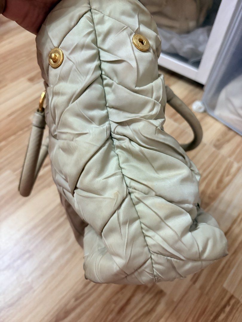 ORIGINAL Prada Quilted Nylon Tote Handbag Off White (Category: Luxury Bags & Wallets) located in Bacoor. Submitted by preownedparadyse (Listing ID 1466753887, Image 2). Description: - Brand: Prada - Style: Quilted nylon tote bag MISSING SLING - Color: light green with gold-tone hardware - Features: Dual top handles, front buckle tag, quilted pattern - Condition: Pre-loved with visible discoloration, stains, and dirt marks on the fabric and corner