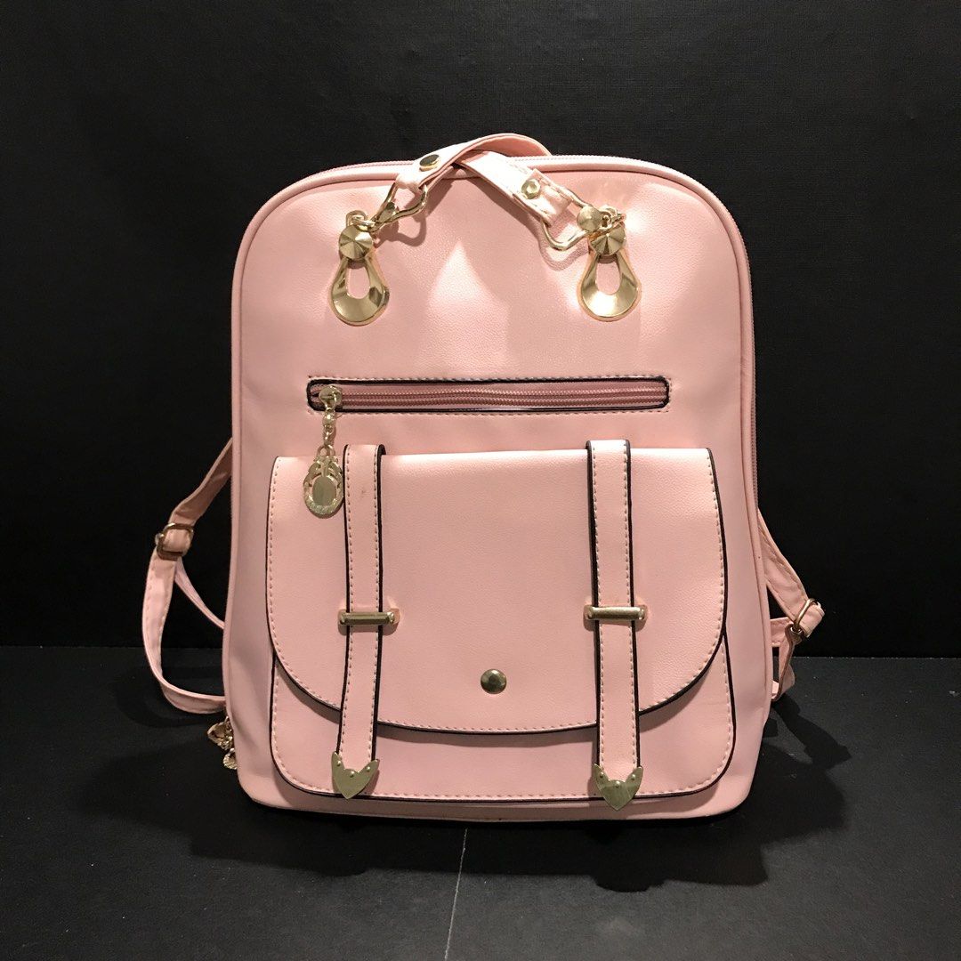 Pink faux leather backpack with gold hardware (Category: Backpacks) located in Baao. Submitted by all.things.japan (Listing ID 1466701589, Image 1). Description: - Color: Soft pink - Material: Smooth synthetic leather with polished gold-tone hardware - Pockets: Front flap pocket with magnetic snap & decorative straps, plus an extra front zippered pocket - Straps: Adjustable matching pink shoulder straps - Closure: Secure zip-around main compartme