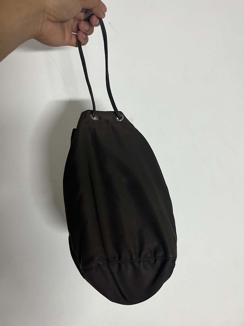 Prada Brown Nylon Bucket Bag (Category: Luxury Bags & Wallets) located in Manila. Submitted by cleverearth.125e3f (Listing ID 1466667536, Image 2). Description: - Authentic Prada nylon bucket bag in a classic brown shade - Made in Italy with durable fabric and silver-tone hardware - Drawstring closure with a secure leather pull - Features the iconic triangular metal logo plaque on the front - Compact and versatile design for shoulder or hand carr