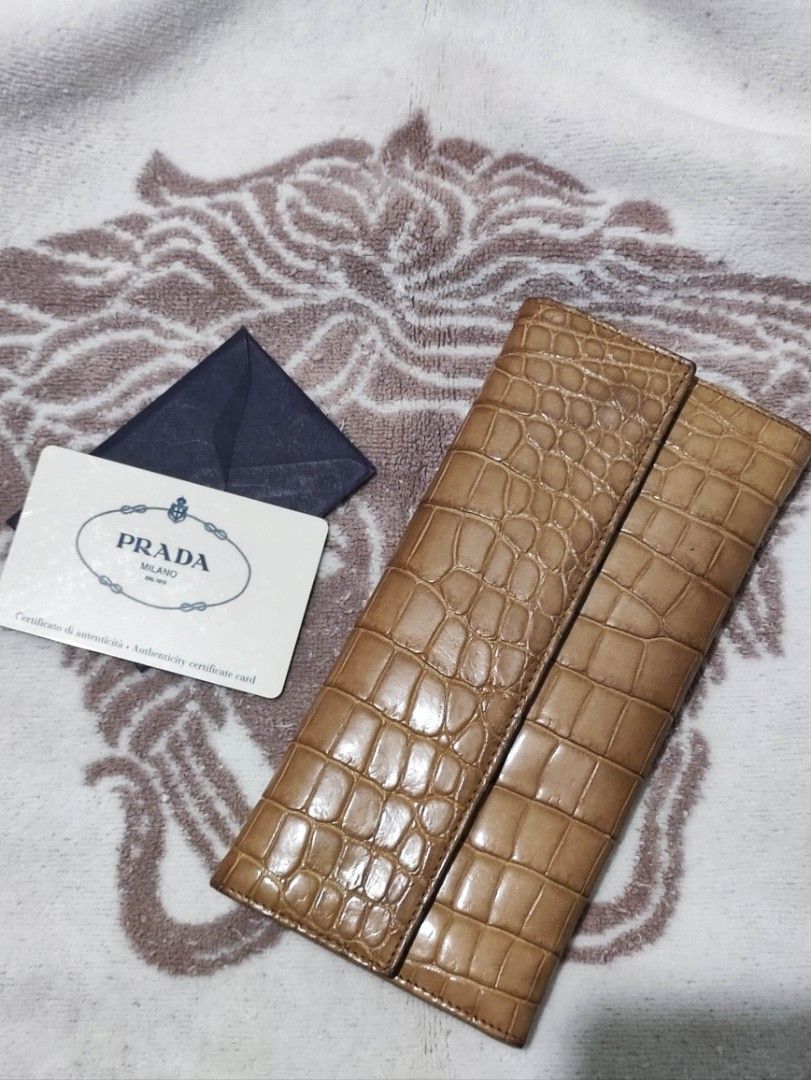 Prada Crocodile Embossed Leather Long Wallet with Authenticity Card (Category: Wallets & Card holders) located in Manila. Submitted by chingmabut07171 (Listing ID 1466607175, Image 1). Description: - Authentic Prada long wallet in rich tan crocodile-embossed leather - Secure bi-fold closure style - Includes original authenticity card and dark blue envelope holder - Spacious interior fits cards, cash, and receipts easily - Classic luxury piece per