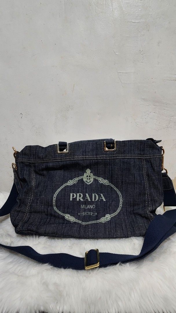Prada Denim Shoulder Bag Handbag (Category: Luxury Bags & Wallets) located in Manila. Submitted by rionbenedicto (Listing ID 1466583180, Image 2). Description: - Brand: Prada - Material: Dark denim with white contrast stitching - Hardware: Gold-tone accents - Design: Embroidered logo on front with a structured rectangular shape - Carry options: Sturdy top handles and a detachable blue canvas shoulder strap - Interior: Spacious enough for daily es