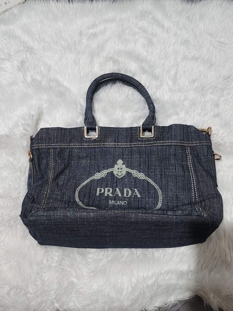 Prada Denim Shoulder Bag Handbag (Category: Luxury Bags & Wallets) located in Manila. Submitted by rionbenedicto (Listing ID 1466583180, Image 1). Description: - Brand: Prada - Material: Dark denim with white contrast stitching - Hardware: Gold-tone accents - Design: Embroidered logo on front with a structured rectangular shape - Carry options: Sturdy top handles and a detachable blue canvas shoulder strap - Interior: Spacious enough for daily es