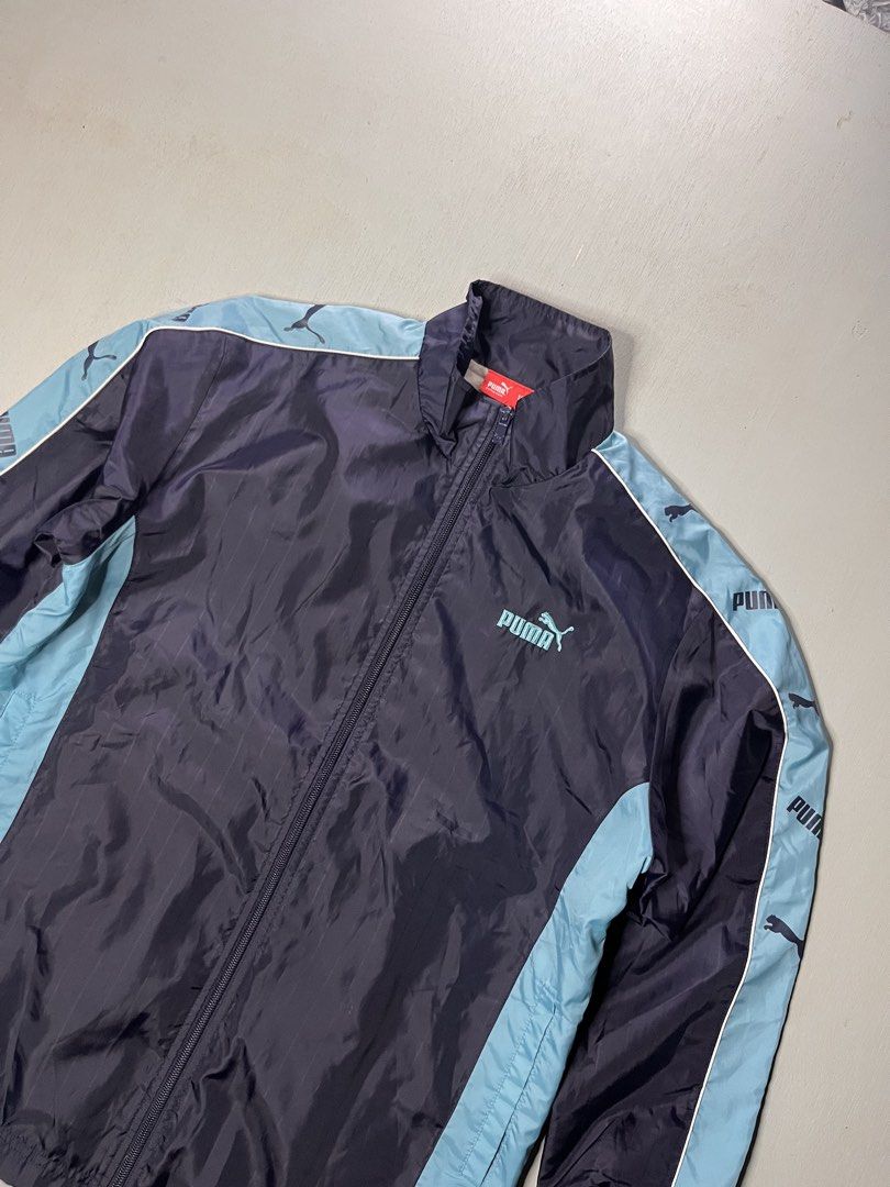 Puma Track Jacket Navy Light Blue Size 150 (Category: Coats, Jackets and Outerwear) located in Catbalogan. Submitted by yellfindss (Listing ID 1466740981, Image 2). Description: - Brand: Puma -20/26 - Color: Navy blue with light blue side panels and sleeve tape - Details: Embroidered light blue Puma logo on chest, full zip front, high collar - Texture: Subtle vertical stripe texture throughout - Size: 150 (indicated on red inner neck tag) - Origi