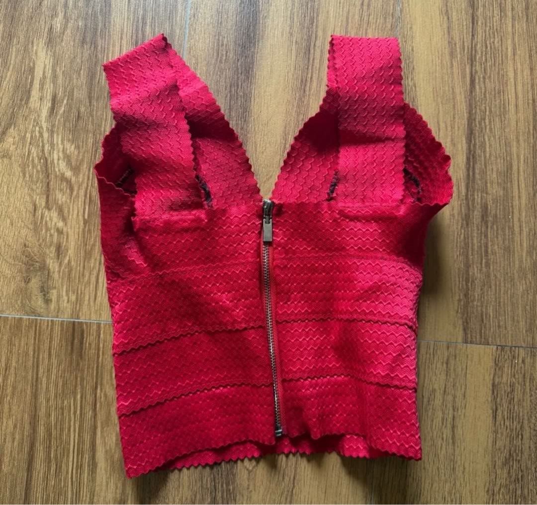 Red bandage crop top sleeveless zip back (Category: Sleeveless) located in Daet. Submitted by k.declutterz (Listing ID 1466620667, Image 2). Description: - Color: Vibrant red - Style: Bandage crop top with bodycon fit - Details: Deep V-neckline, wide straps, and scalloped edges - Material: Thick, structured fabric with a subtle texture - Closure: Exposed silver zipper running down the entire back - Pairing: Great with high-waisted jeans or skirts
