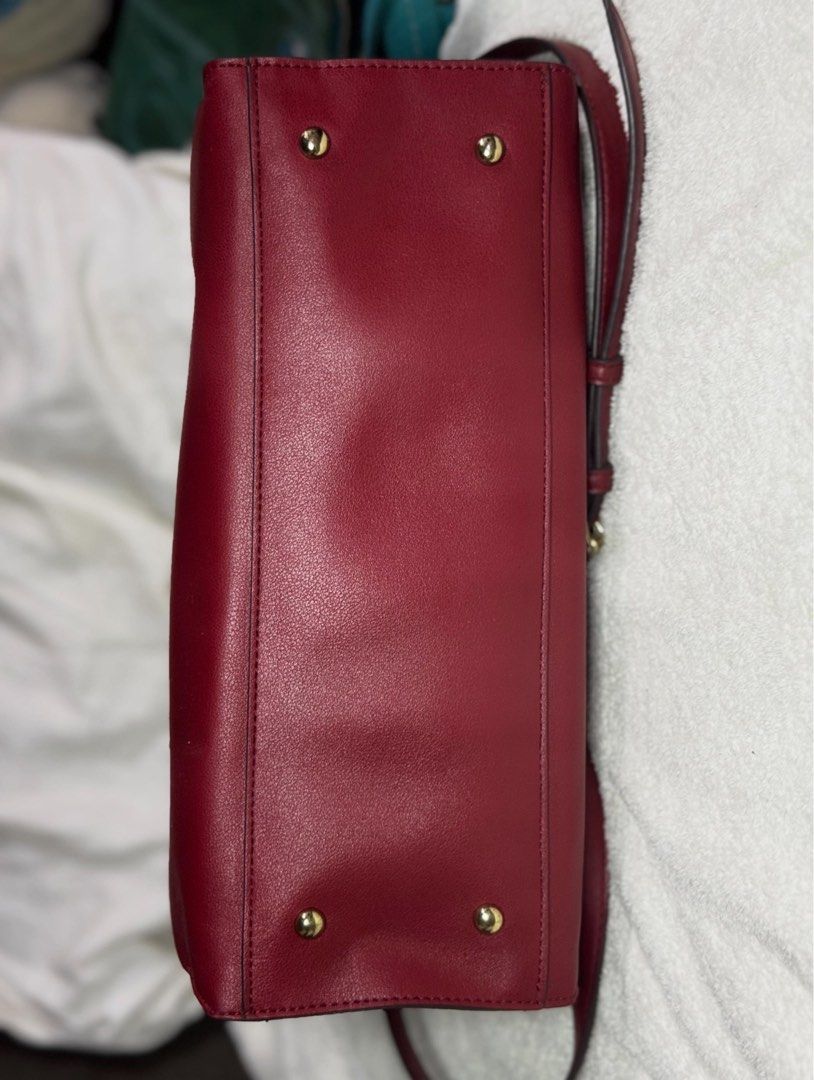 Red Structured Tote Bag With Crossbody Strap (Category: Tote Bags) located in Manila. Submitted by rosseeyycheeks (Listing ID 1466652779, Image 3). Description: Structured red handbag with gold-tone hardware. Double top handles and a detachable shoulder strap included. Front exterior slip pocket with a dangling circle charm. Multiple interior compartments with zip closures and dark fabric lining. Base features four protective metal feet. Interior