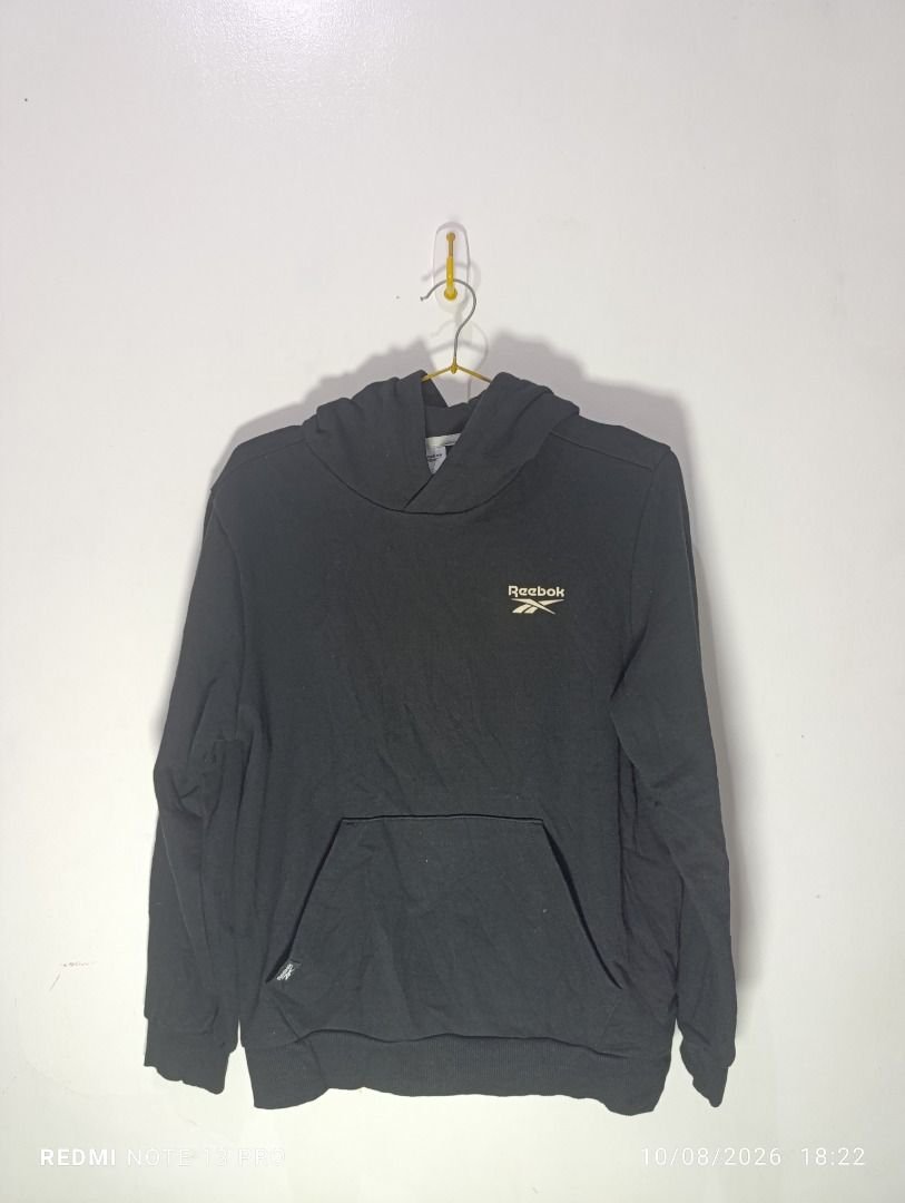 Reebok Black Hoodie Pullover (Category: Coats, Jackets and Outerwear) located in Pasig City. Submitted by firstpick_thrift (Listing ID 1466772343, Image 1). Description: - Brand: Reebok - Color: Black - Style: Classic pullover hoodie with front pocket - Details: Small logo on front chest, crossover hood design - Fit: Snug ribbed cuffs and hem - Material: Soft and comfortable fabric, perfect for daily wear - Easy to pair with jeans or sweatpants.