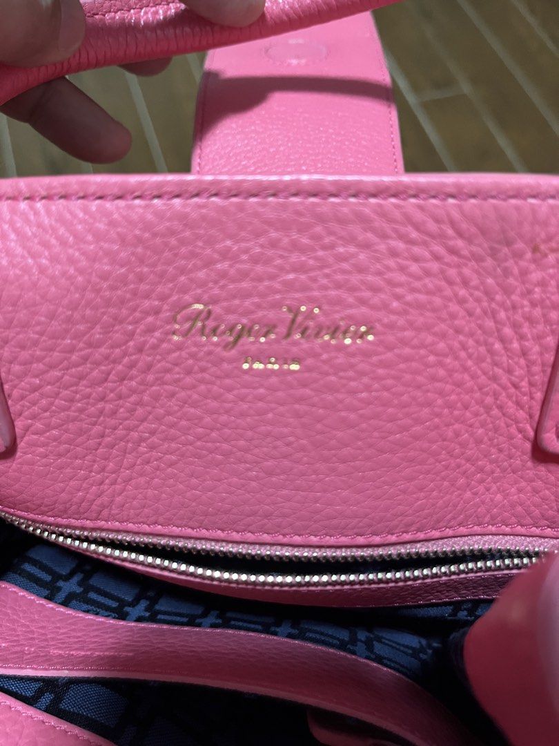 Roger Vivier Pink Leather Handbag (Category: Luxury Bags & Wallets) located in Victorias. Submitted by lan1877 (Listing ID 1466772547, Image 3). Description: Bright pink leather handbag from Roger Vivier. Double top handles with matching tag pendant. Front buckle detail and belted side accents with metallic studs. Zip closure across the top with patterned fabric lining inside. Gold foil logo stamped near the zipper. Clean shape with sturdy base..