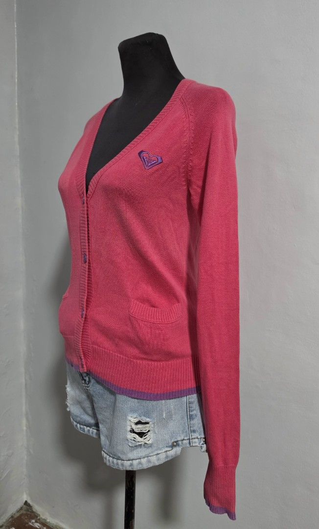 Roxy Pink Button-Up Knit Cardigan Size M (Category: Coats, Jackets and Outerwear) located in Paranaque City. Submitted by franinnashop (Listing ID 1466613220, Image 2). Description: DECLUTTER SMALL TO MED ISSUE LAST PHOTO NOT SURE IF DISCOLORATION OR ALIKABOK PARANAQUE CITY Roxy pink button-up cardigan in size medium. V-neck cut with purple contrast buttons and matching purple trim at the hem and cuffs. Small embroidered Roxy heart logo on the le