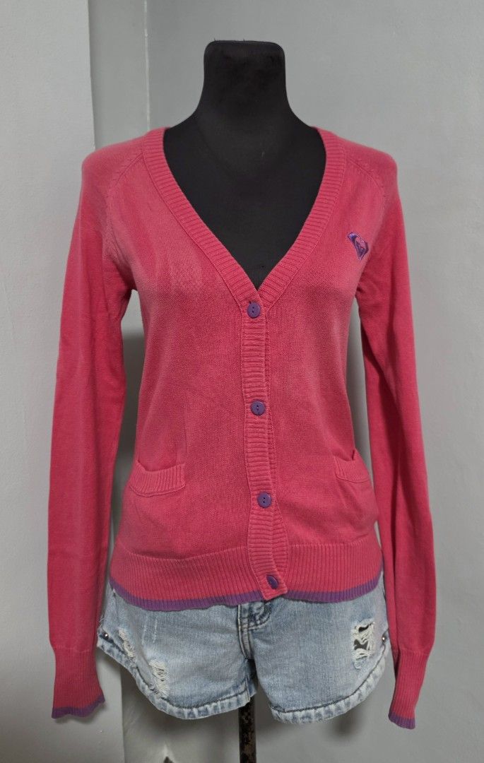 Roxy Pink Button-Up Knit Cardigan Size M (Category: Coats, Jackets and Outerwear) located in Paranaque City. Submitted by franinnashop (Listing ID 1466613220, Image 1). Description: DECLUTTER SMALL TO MED ISSUE LAST PHOTO NOT SURE IF DISCOLORATION OR ALIKABOK PARANAQUE CITY Roxy pink button-up cardigan in size medium. V-neck cut with purple contrast buttons and matching purple trim at the hem and cuffs. Small embroidered Roxy heart logo on the le