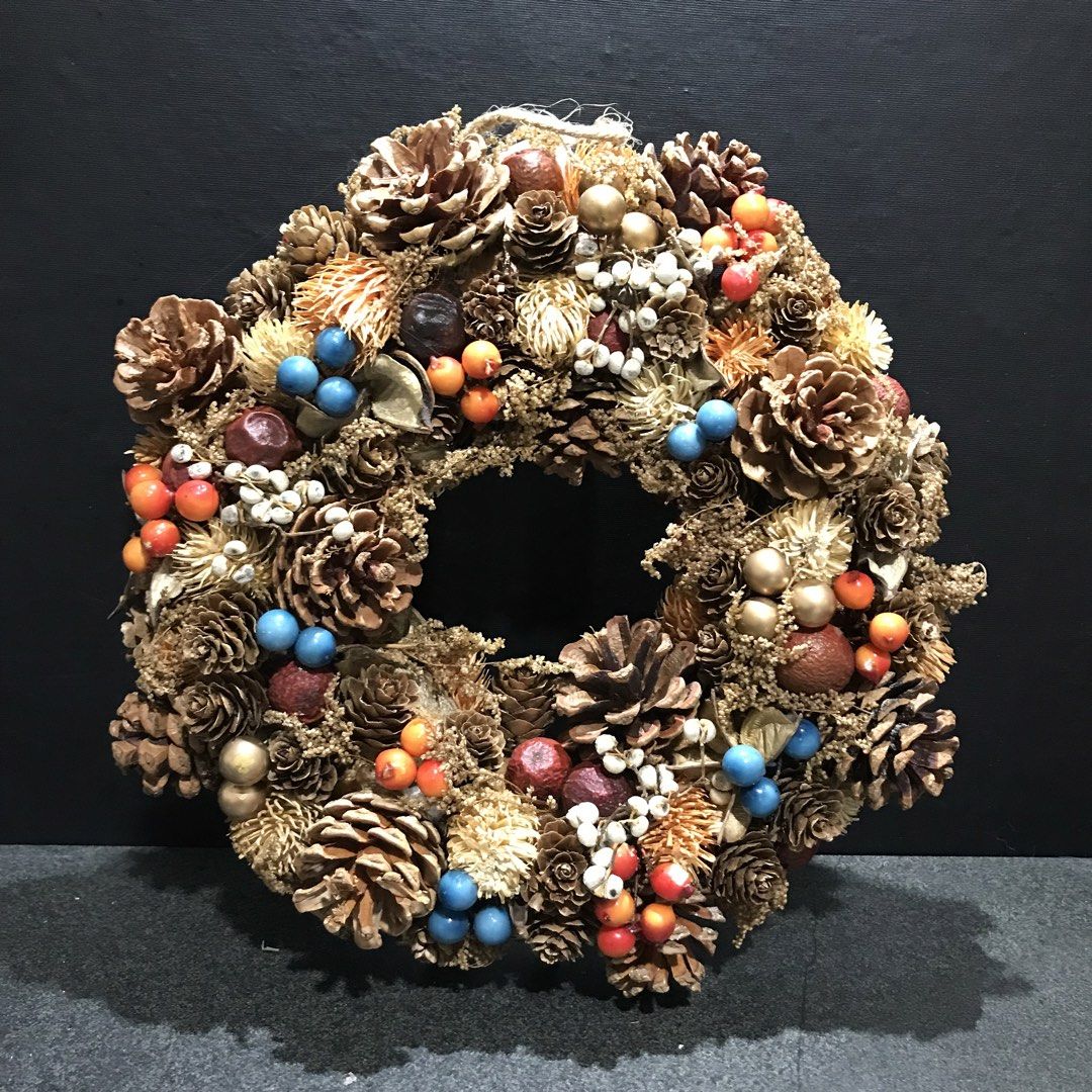 Rustic Pinecone and Berry Decorative Christmas Wreath (Category: Wall Decor) located in Baao. Submitted by all.things.japan (Listing ID 1466714903, Image 2). Description: 28.0 cm/11.0 inches diameter - Size: Measures approx. 30cm across - Materials: Natural pinecone base decorated with dried flowers, berries, and seed pods - Accents: Features blue, orange, and red berries, gold touches, and white sprigs - Finishing: Clean brown paper backing with