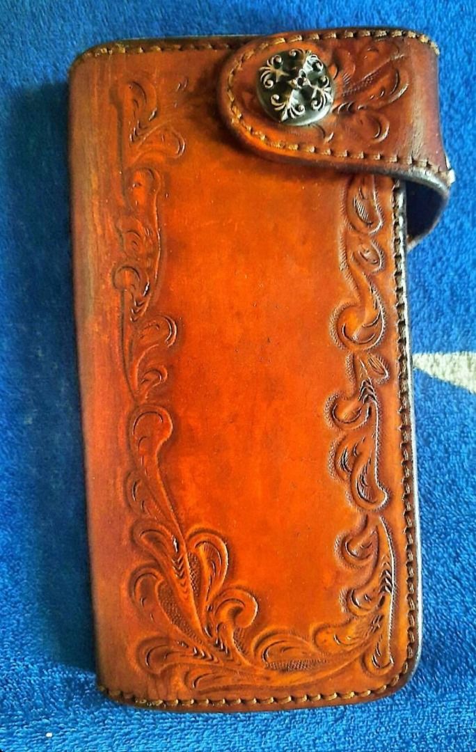 SAAD Leather Long Wallet Tooled Design (Category: Wallets & Card holders) located in Santa Cruz. Submitted by freeturtle_2610 (Listing ID 1466764490, Image 3). Description: - Brand: SAAD - Material: Genuine leather in tan brown - Exterior: Hand-tooled floral carved pattern with a snap button closure and decorative metal concho - Interior: Multiple card slots, spacious bill compartments, and a zippered coin pocket - Details: Stamped with the SAAD 