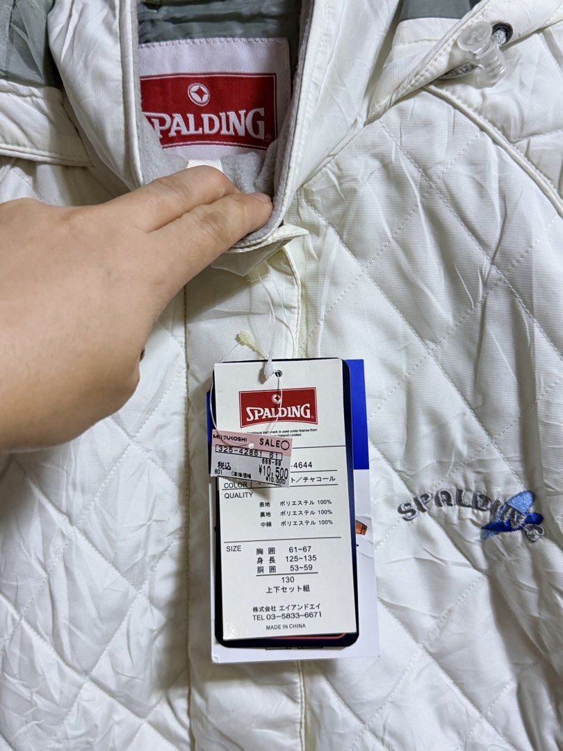 Spalding Quilted Winter Jacket Size 130 White (Category: Babies & Kids Fashion) located in Paete. Submitted by skydruemadison (Listing ID 1466687421, Image 2). Description: Spalding quilted jacket in off-white and charcoal gray. Includes original store tags attached with price details. Hooded design with front zipper and snap button closure. Interior mesh pocket and personal identification label inside. Quilted pattern throughout the exterior wit