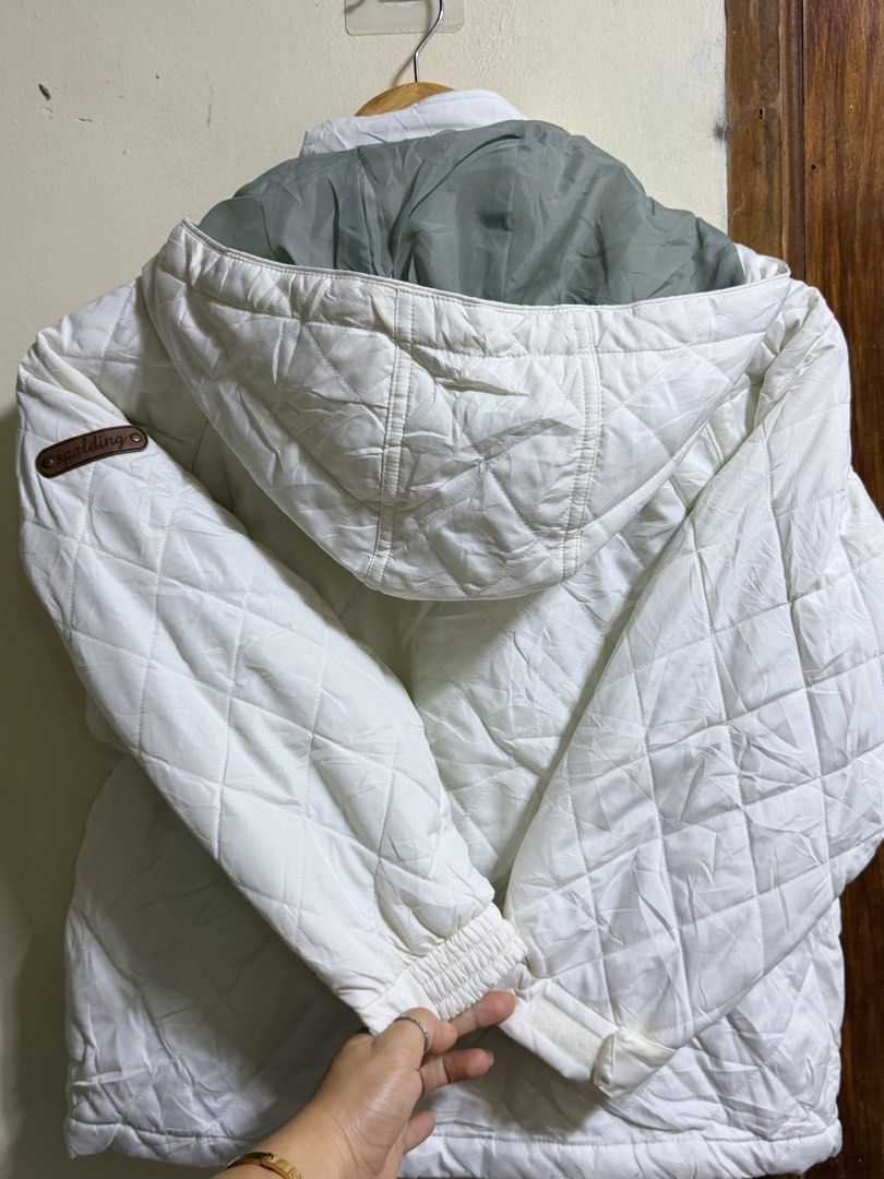 Spalding Quilted Winter Jacket Size 130 White (Category: Babies & Kids Fashion) located in Paete. Submitted by skydruemadison (Listing ID 1466687421, Image 3). Description: Spalding quilted jacket in off-white and charcoal gray. Includes original store tags attached with price details. Hooded design with front zipper and snap button closure. Interior mesh pocket and personal identification label inside. Quilted pattern throughout the exterior wit