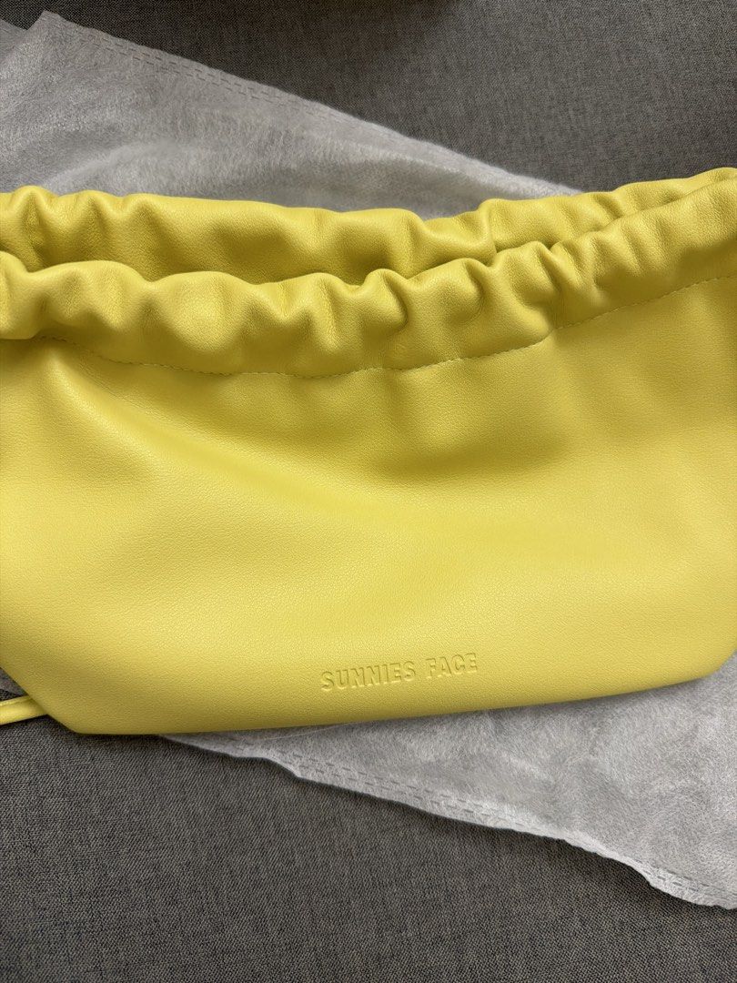 Sunnies Face yellow dumpling pouch bag (Category: Purses & Pouches) located in Manila. Submitted by scimihx (Listing ID 1466675470, Image 1). Description: - Brand: Sunnies Face - Color: Bright yellow - Material & Design: Soft fabric with a gathered drawstring top and debossed front logo - Condition: Clean exterior, no marks or stains (comes with white dust bag) - Usage: Ideal for daily essentials or makeup storage.