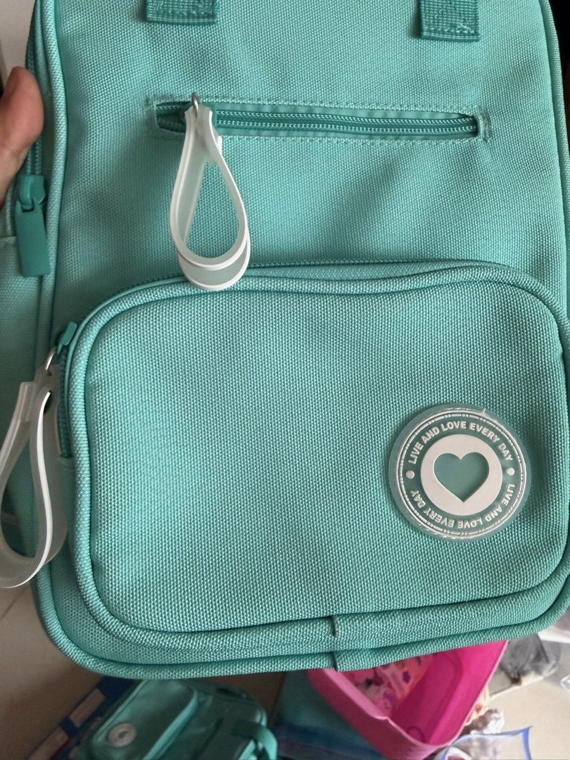 Teal Backpack with Heart Motif (Category: Babies & Kids Fashion) located in Quezon City. Submitted by bubspreloved (Listing ID 1466771077, Image 3). Description: - used once (Original US $24.99) - Color: Vibrant teal with white zipper pulls - Features a cute 'LIVE AND LOVE EVERY DAY' heart patch on the front - Practical design with adjustable straps and front zip pocket - Clean fabric construction, perfect for school or daily use.