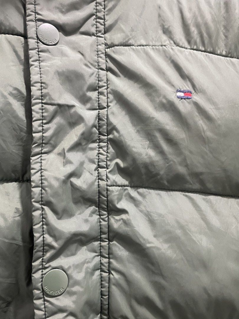 Tommy Hilfiger Green Puffer Jacket (Category: Coats, Jackets and Outerwear) located in Manila. Submitted by oenthrift.2026 (Listing ID 1466709141, Image 3). Description: - Brand: Tommy Hilfiger - Color: Olive green with bright orange inner lining - Design: High collar with ribbed inner lining, full zip and snap button closure - Details: Iconic embroidered flag logo on the left chest - Pockets: Two functional front slash pockets - Warmth: Heavy qu