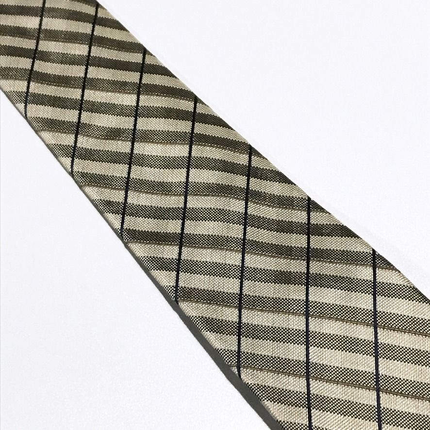 TOPVALU Woven Checkered Beige Neck Tie (Category: Ties) located in Taguig. Submitted by retrogaze (Listing ID 1466678990, Image 3). Description: This 100% silk necktie by TOPVALU features a beige base woven with a rich, multi-textured geometric grid structure. The design displays alternating ribbed and micro-textured diagonal bands framed by subtle olive-green pinstripes and crisscrossing navy blue windowpane lines. Brand Overview: TOPVALU is a w