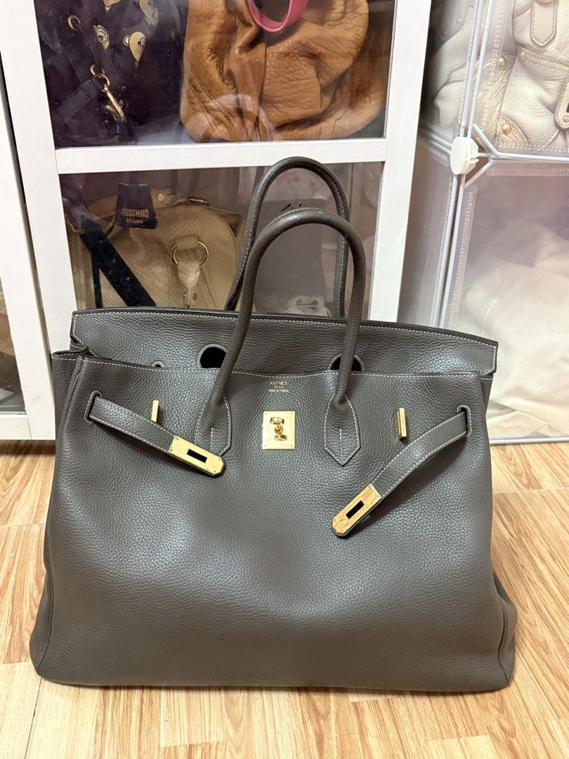 Tote Size 40cm, birkin-style (Category: Luxury Bags & Wallets) located in Bacoor. Submitted by preownedparadyse (Listing ID 1466752760, Image 2). Description: - Color/Material: Dark grey textured leather with contrast stitching - Hardware: gold-tone hardware - Closure: Signature turnlock closure - Handles: Dual rolled top handles for comfortable carrying - Interior: Spacious daily carryall with a zippered pocket and pull tab - Base: Structured ba