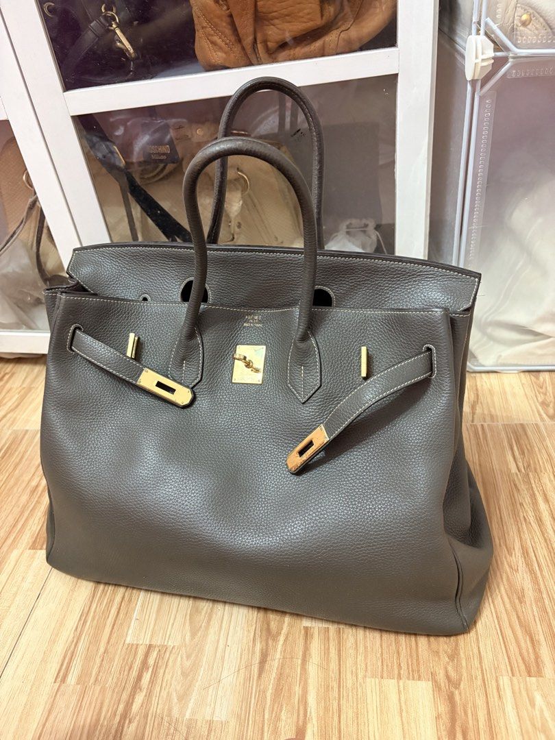 Tote Size 40cm, birkin-style (Category: Luxury Bags & Wallets) located in Bacoor. Submitted by preownedparadyse (Listing ID 1466752760, Image 1). Description: - Color/Material: Dark grey textured leather with contrast stitching - Hardware: gold-tone hardware - Closure: Signature turnlock closure - Handles: Dual rolled top handles for comfortable carrying - Interior: Spacious daily carryall with a zippered pocket and pull tab - Base: Structured ba