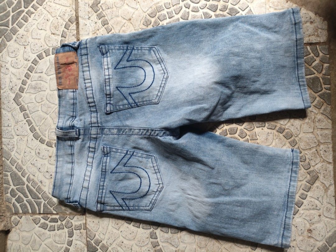 True Religion Denim Shorts Size 12 (Category: Shorts) located in Libungan. Submitted by raycal9 (Listing ID 1466613297, Image 2). Description: - Brand: True Religion - Size: 12 - Color: Light blue wash - Fit: Relaxed slim fit - Details: Moto-style pleated ribbing panels on front legs - Pockets: Classic horseshoe stitching on back pockets - Branding: Leather logo patch on back waistband and branded hardware - Closure: Button closure.