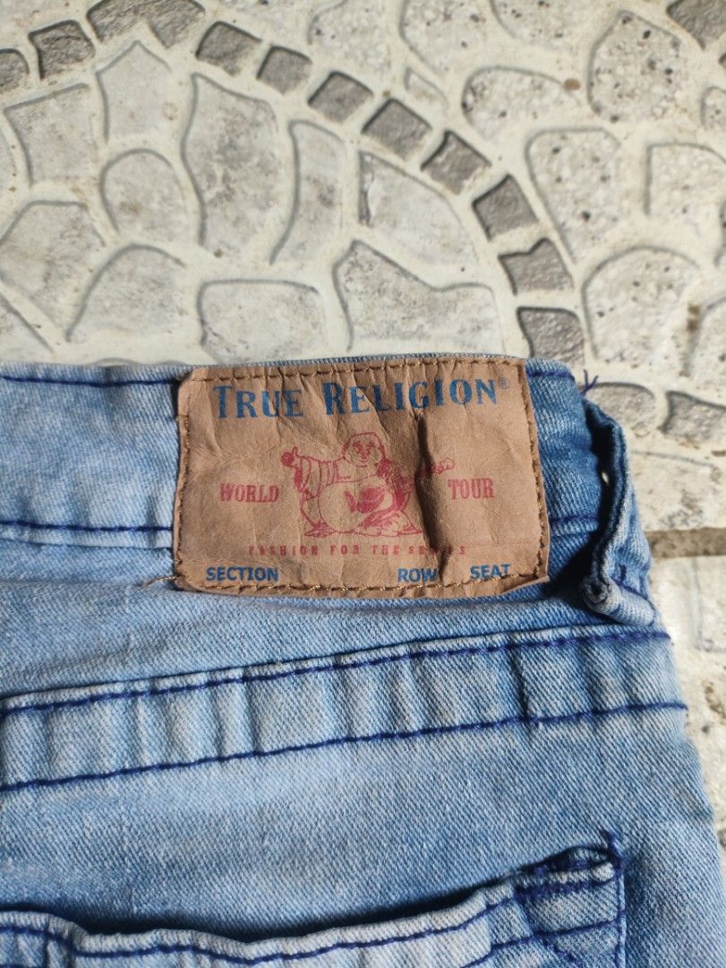 True Religion Denim Shorts Size 12 (Category: Shorts) located in Libungan. Submitted by raycal9 (Listing ID 1466613297, Image 3). Description: - Brand: True Religion - Size: 12 - Color: Light blue wash - Fit: Relaxed slim fit - Details: Moto-style pleated ribbing panels on front legs - Pockets: Classic horseshoe stitching on back pockets - Branding: Leather logo patch on back waistband and branded hardware - Closure: Button closure.