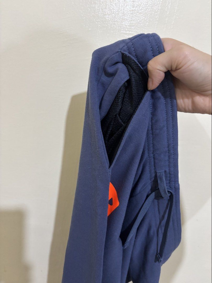 Under Armour Blue Joggers Sweatpants (Category: Joggers) located in Balayan. Submitted by authenticfindsbymrb (Listing ID 1466702462, Image 2). Description: - Brand/Item: Blue Under Armour sweatpants - Fit: Standard fit with adjustable drawstring waist and cuffed ankles - Design: Bright orange logo graphic on the right leg - Pockets: Two deep side pockets with mesh lining - Material: Soft cotton blend with cozy French terry inner lining - Use: Id