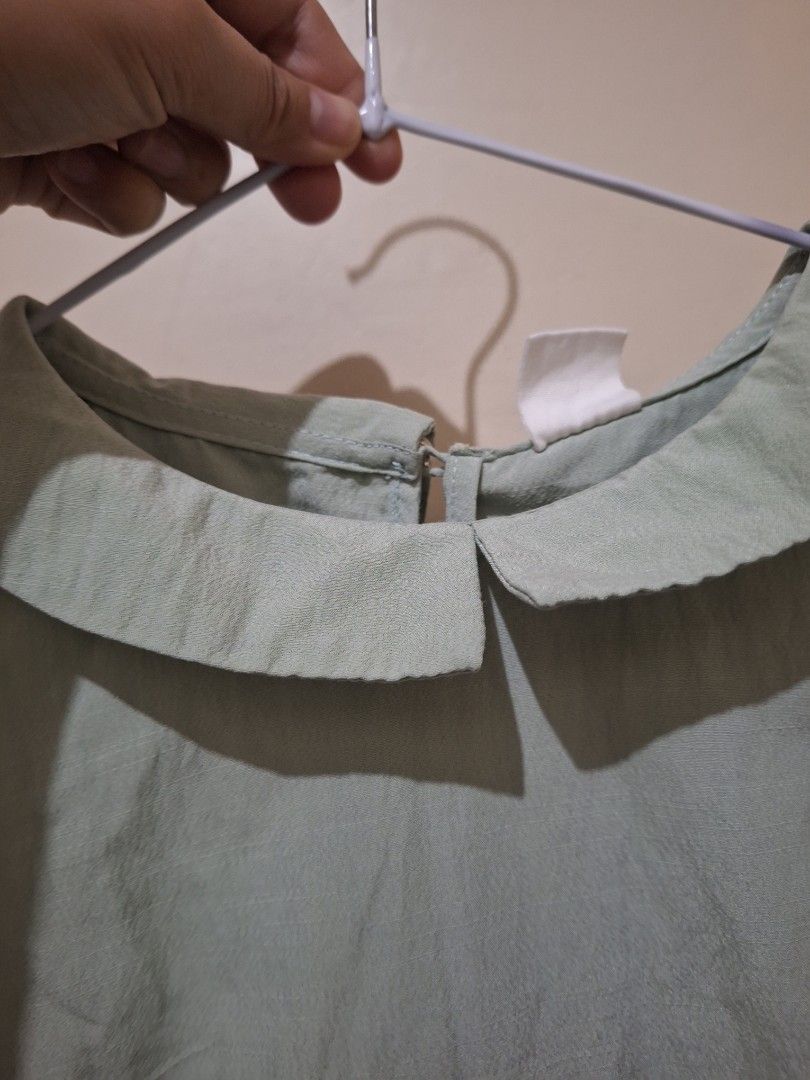 UNICA blouse (Category: Blouses) located in Quezon City. Submitted by meibunny (Listing ID 1466604576, Image 1). Description: - Brand: UNICA - Color: Sage Green - Size: XS but fits up to Medium - Design: Peter Pan collar with back button closure, 3/4 sleeves with gathered ruching and small wooden logo tag - Fit: Relaxed and lightweight - Condition: Clean and well-maintained.