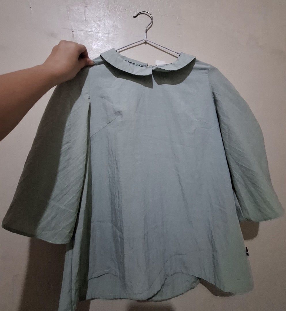 UNICA blouse (Category: Blouses) located in Quezon City. Submitted by meibunny (Listing ID 1466604576, Image 2). Description: - Brand: UNICA - Color: Sage Green - Size: XS but fits up to Medium - Design: Peter Pan collar with back button closure, 3/4 sleeves with gathered ruching and small wooden logo tag - Fit: Relaxed and lightweight - Condition: Clean and well-maintained.