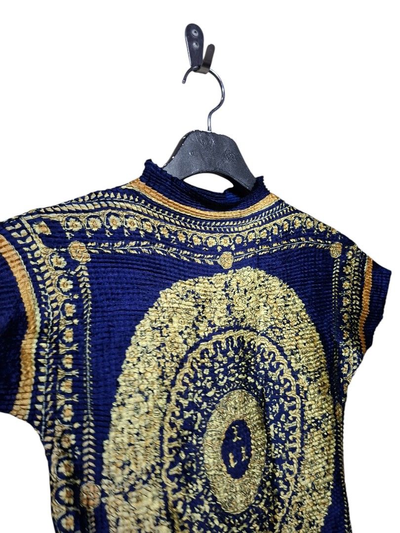 Versace Pleated Silk Top (Category: Luxury Apparel) located in Leyte. Submitted by jpsrvd19 (Listing ID 1466691414, Image 2). Description: - Versace Pleated Silk Top - Color/Print: Deep blue with a striking gold baroque medallion and floral print - Material: Lightweight, crinkled, and stretchy texture for a comfortable fit - Design: Mock neck collar and short cap sleeves - Details: Bold circular chest pattern and stitched Versace label inside - F