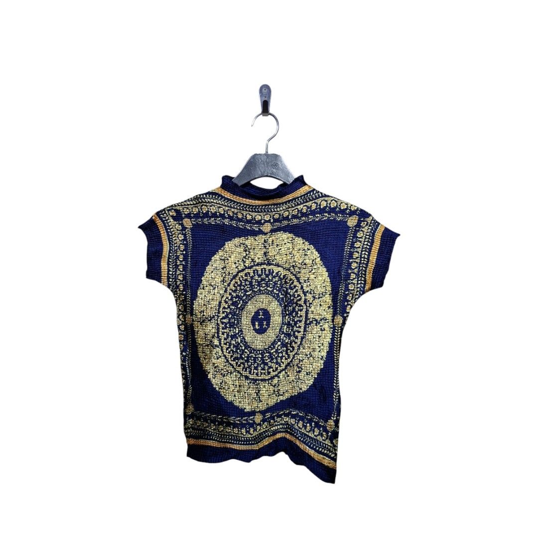 Versace Pleated Silk Top (Category: Luxury Apparel) located in Leyte. Submitted by jpsrvd19 (Listing ID 1466691414, Image 1). Description: - Versace Pleated Silk Top - Color/Print: Deep blue with a striking gold baroque medallion and floral print - Material: Lightweight, crinkled, and stretchy texture for a comfortable fit - Design: Mock neck collar and short cap sleeves - Details: Bold circular chest pattern and stitched Versace label inside - F