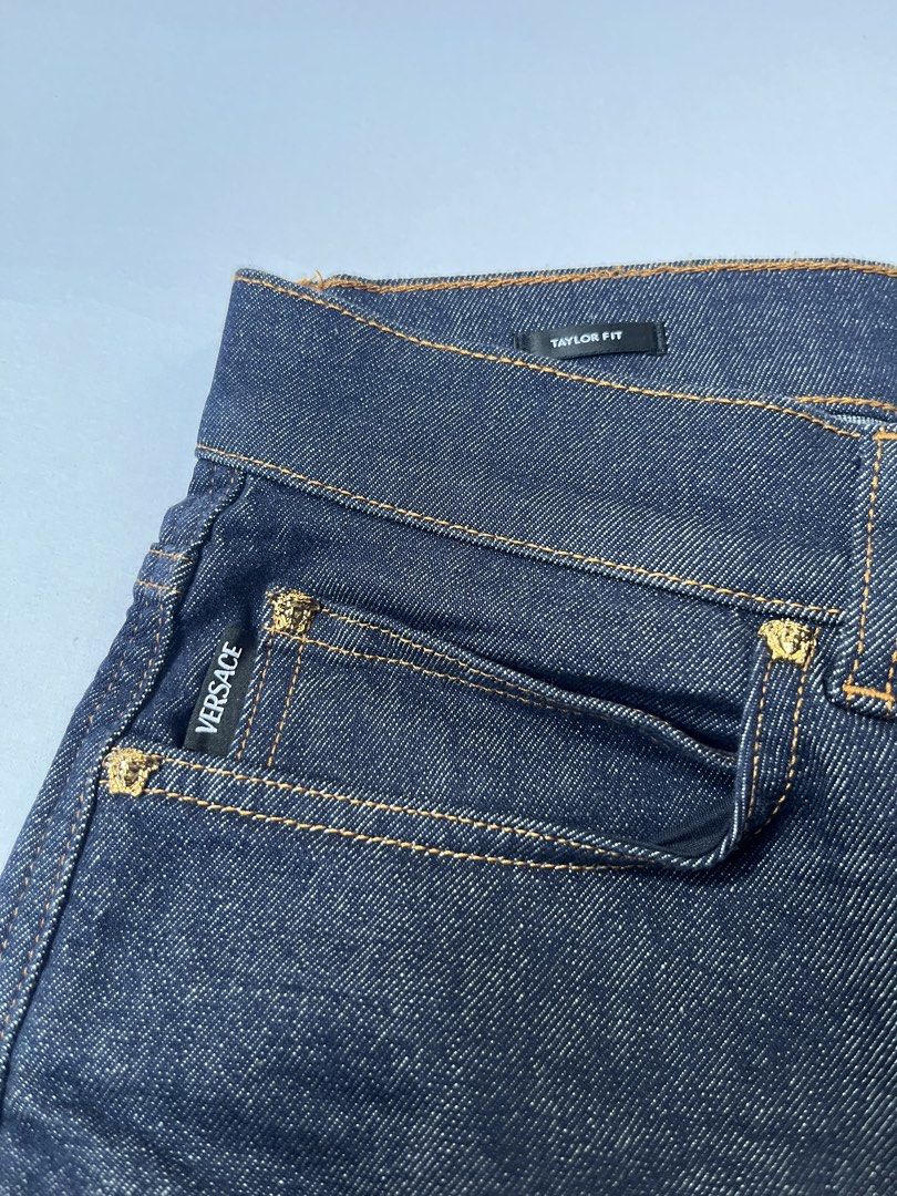 Versace Taylor Fit Dark Denim Jeans (Category: Jeans) located in Dumangas. Submitted by chiiieeef (Listing ID 1466566047, Image 3). Description: - Brand: Versace - Model: Taylor Fit Jeans - Color: Dark Indigo Denim - Material: Made in Italy - Design: Classic five-pocket setup with orange contrast stitching - Hardware: Gold-tone featuring the iconic Medusa head motif on button and rivets - Branding: Black leather rear waistband patch with embossed