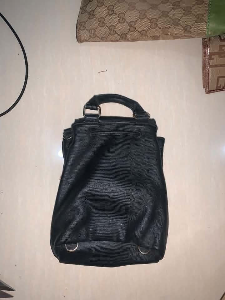 Victoria's Secret Black Textured Mini Backpack (Category: Backpacks) located in Tiaong. Submitted by cdoswan (Listing ID 1466622251, Image 2). Description: - Brand: Victoria's Secret - Material: Premium black faux leather with all-over textured pattern - Closure: Flap closure with secure drawstring mechanism underneath - Details: Signature metal logo plate on the front - Comfort & Carry: Top handle and adjustable shoulder straps - Size: Compact a