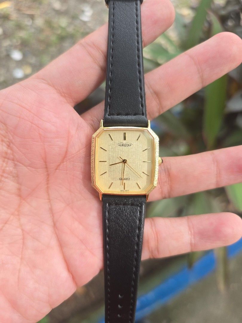Vintage Aureole Swiss Tank Quart (Category: Luxury Watches) located in Manila. Submitted by timearcph (Listing ID 1466606315, Image 2). Description: • Case Style: Rectangular/octagonal "Tank" style case featuring an elegant, bark-textured or hammered finish on the gold-plated bezel. • Dial: Champagne/gold-toned vertical linen-textured dial. It features a minimalist layout with golden stick/baton hour indices and a clean, three-hand configuration 