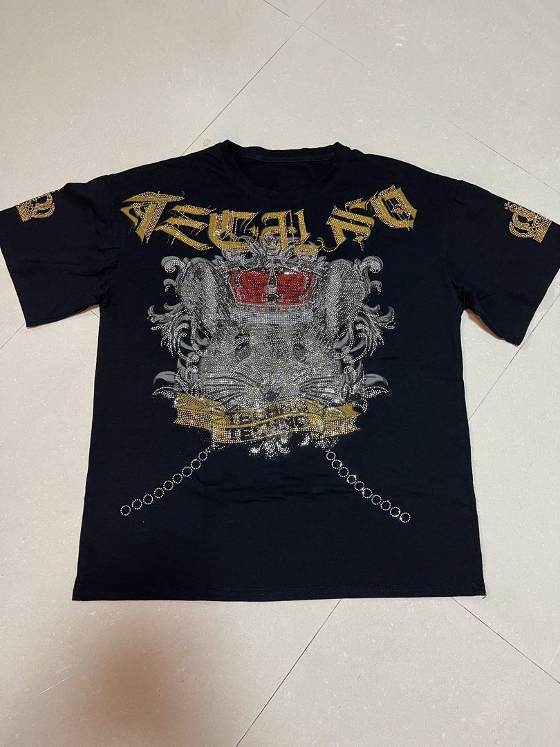 VINTAGE Y2K AFFLICTION STYLE (Category: Shirts) located in Guiguinto. Submitted by junibunn (Listing ID 1466574483, Image 1). Description: - 22x26 - Color & Fit: Black, regular fit - Material: 100% cotton - Front Design: Detailed crown and animal face in silver, black, and gold rhinestones - Back Design: Large silver rhinestone angel wings with a red cross chain graphic - Sleeve Detail: Small rhinestone crowns - Condition: Brand new / Excellent.