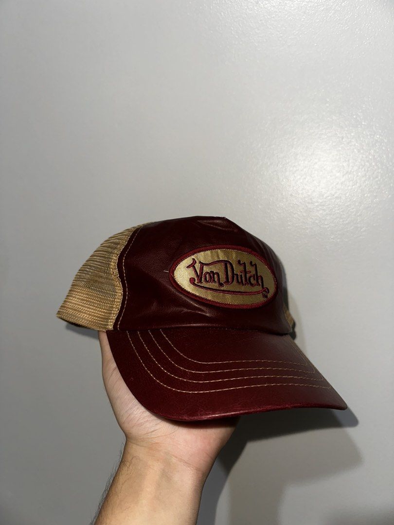 Von Dutch Trucker Hat Maroon and Tan (Category: Caps & Hats) located in Manila. Submitted by driftthrift (Listing ID 1466760221, Image 1). Description: - Brand: Von Dutch - Color: Maroon front with tan mesh back - Design: Gold embroidered logo patch and leather-look brim - Closure: Adjustable snapback - Condition: Clean overall, with clear inside tags for authenticity.