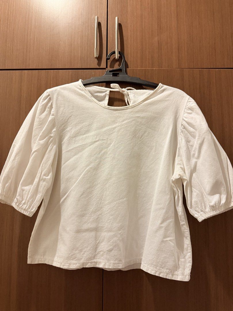 White Blouse with Puff Sleeves and Back Tie (Category: Blouses) located in Pasig City. Submitted by shop.gelss (Listing ID 1466770094, Image 1). Description: - Color: White - Material: Lightweight cotton, loose fit - Details: Puffed shoulders, elastic cuffs, and back cutout with neck tie closure - Styling: Easy to match with jeans or skirts - Condition: Brand new / Excellent.