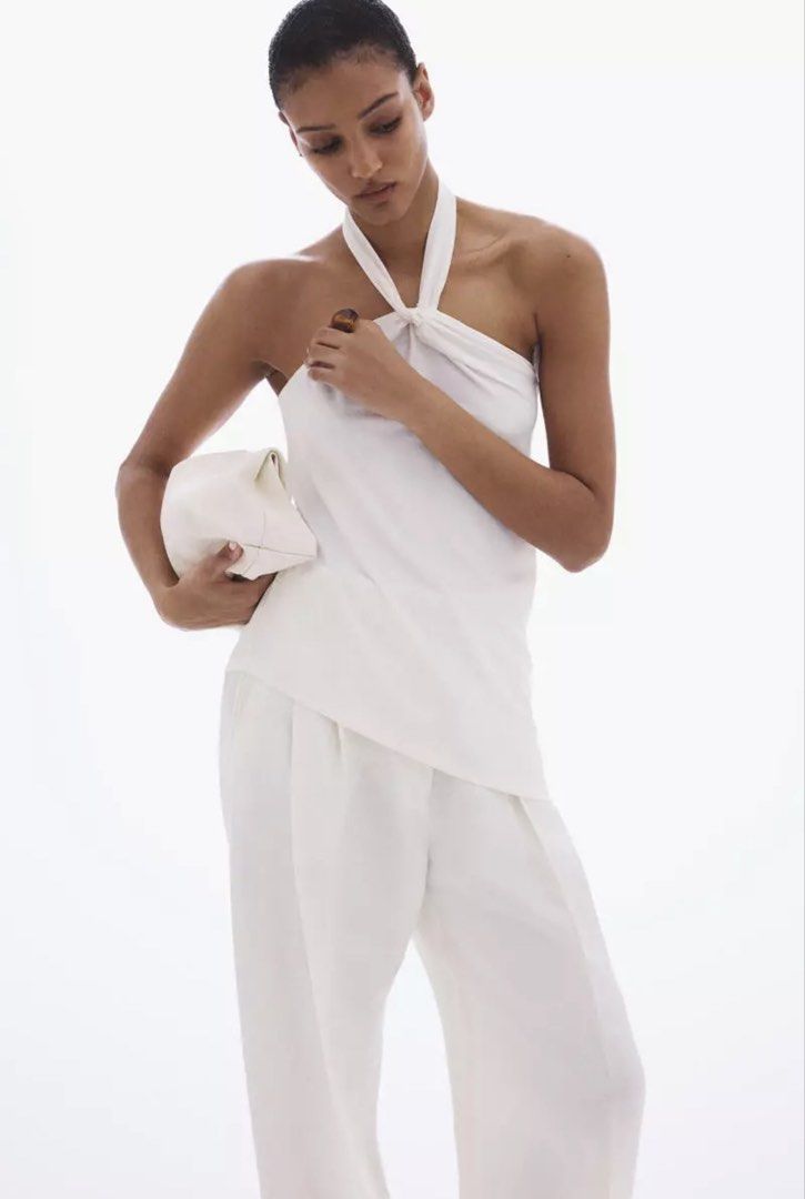 White halter neck draped sleeveless top (Category: Sleeveless) located in Manila. Submitted by katrinakatee (Listing ID 1466672841, Image 2). Description: - Color: White - Style: Halter neck with knot detail and draped front - Fit: Standard fit with thin straps - Fabric: Soft and comfortable - Versatile: Easy to pair with skirts or trousers for casual days or nights out.
