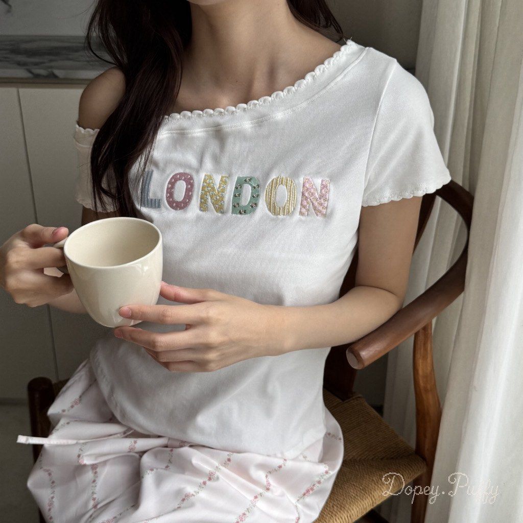 White LONDON Off Shoulder Top (Category: Shirts) located in Pasig City. Submitted by luckyvicky_ (Listing ID 1466736283, Image 1). Description: - Color: White - Sleeve: Short sleeve - Neckline: Scallop trim - Design: Colorful patterned fabric embroidered "LONDON" letters - Material: Soft cotton - Fit: Comfortable - Versatile: Great for everyday wear, easily pairs with lounge pants or casual bottoms.