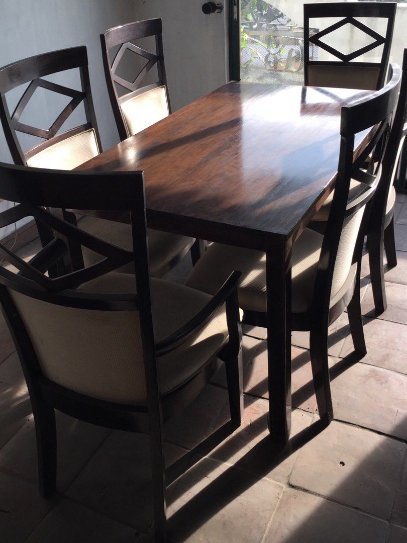 Wooden Dining Table with Six Chairs (Category: Tables & Sets) located in Manila. Submitted by roberto.enriquez (Listing ID 1466768518, Image 3). Description: Dark wood dining table and six matching chairs. Cream-colored upholstered seats. Geometric diamond pattern cut out on the upper backrests of each chair. Two end chairs include wooden armrests. Sturdy build, classic dark finish. Table seats six comfortably. Great setup for family meals or hos