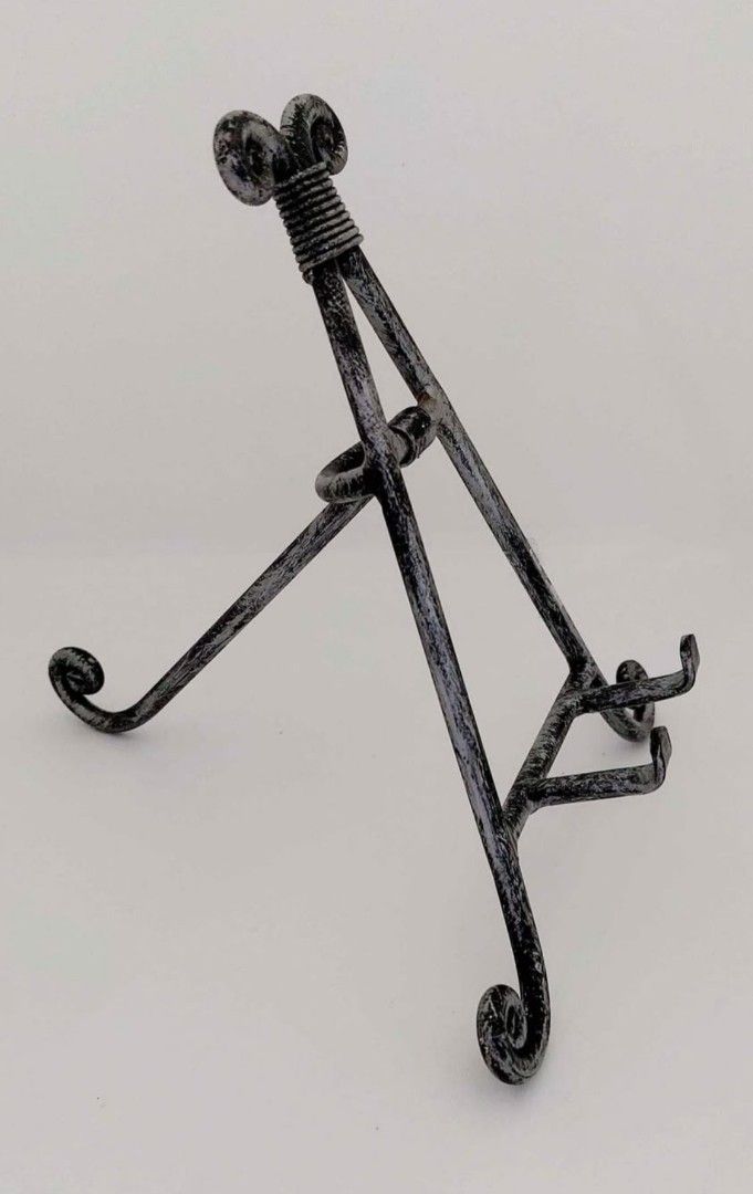 Wrought Iron Decorative Plate Display Stand Easel (Category: Wall Decor) located in Cainta. Submitted by veronica2277 (Listing ID 1466655648, Image 2). Description: - Elegant metal easel stand with a distressed silver and black finish - Features decorative scrollwork at the top and bottom feet - Adjustable back support leg for stable placement on tables or shelves - Securely holds heavy decor plates, picture frames, or decorative tiles - Compact 