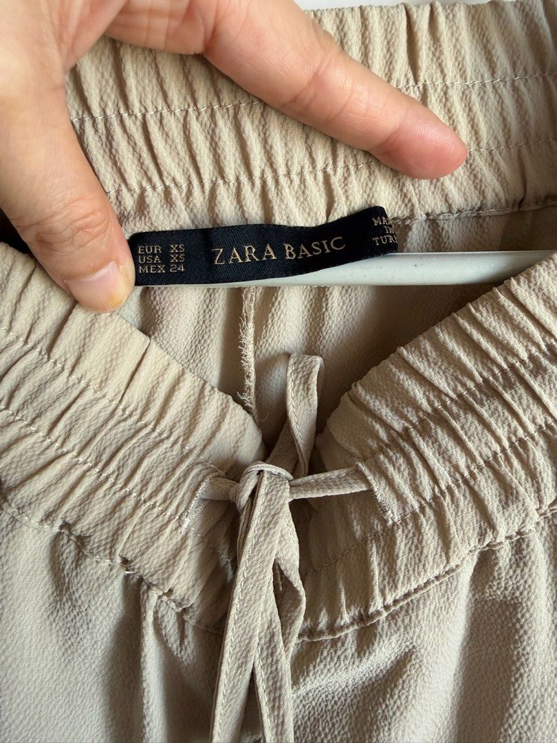 Zara Basic Beige Drawstring Pants Size XS (Category: Joggers) located in Quezon City. Submitted by bubspreloved (Listing ID 1466722593, Image 3). Description: - Brand: Zara Basic - Color: Light Beige - Size: XS - Material: Lightweight fabric with slightly textured finish - Features: Elastic waistband with drawstring and silver aglets, side pockets - Origin: Made in Turkey - Condition: Clean and ready to wear.